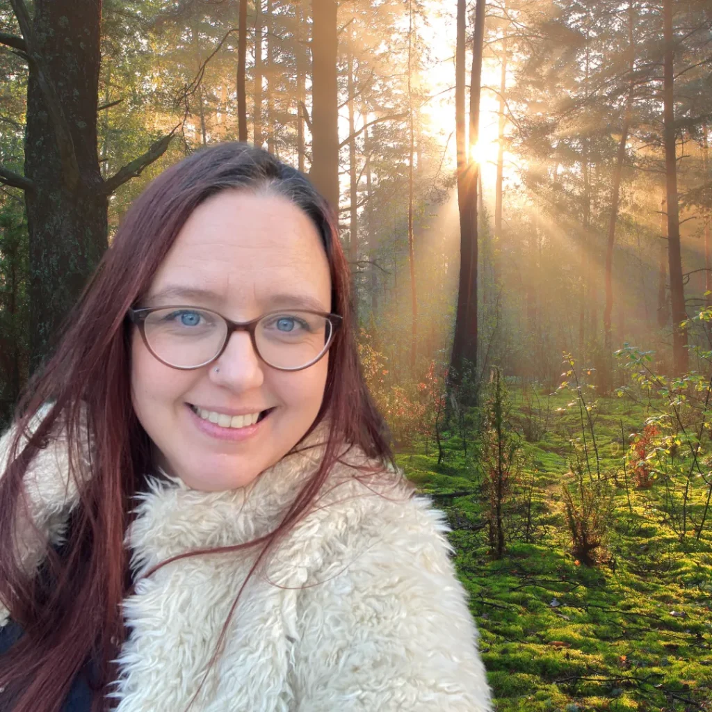 Helen Edgar, community educator and autistic advocate, smiling in a sunlit forest setting