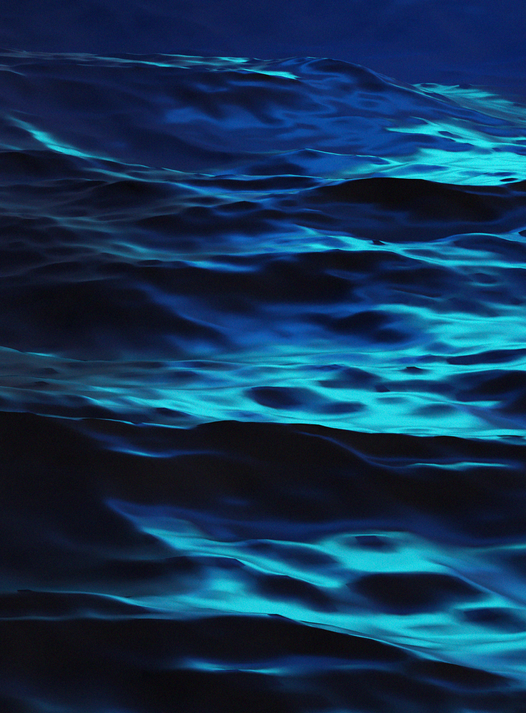 Image of dark blue water rippling, with bright turquoise light reflecting off the waves.