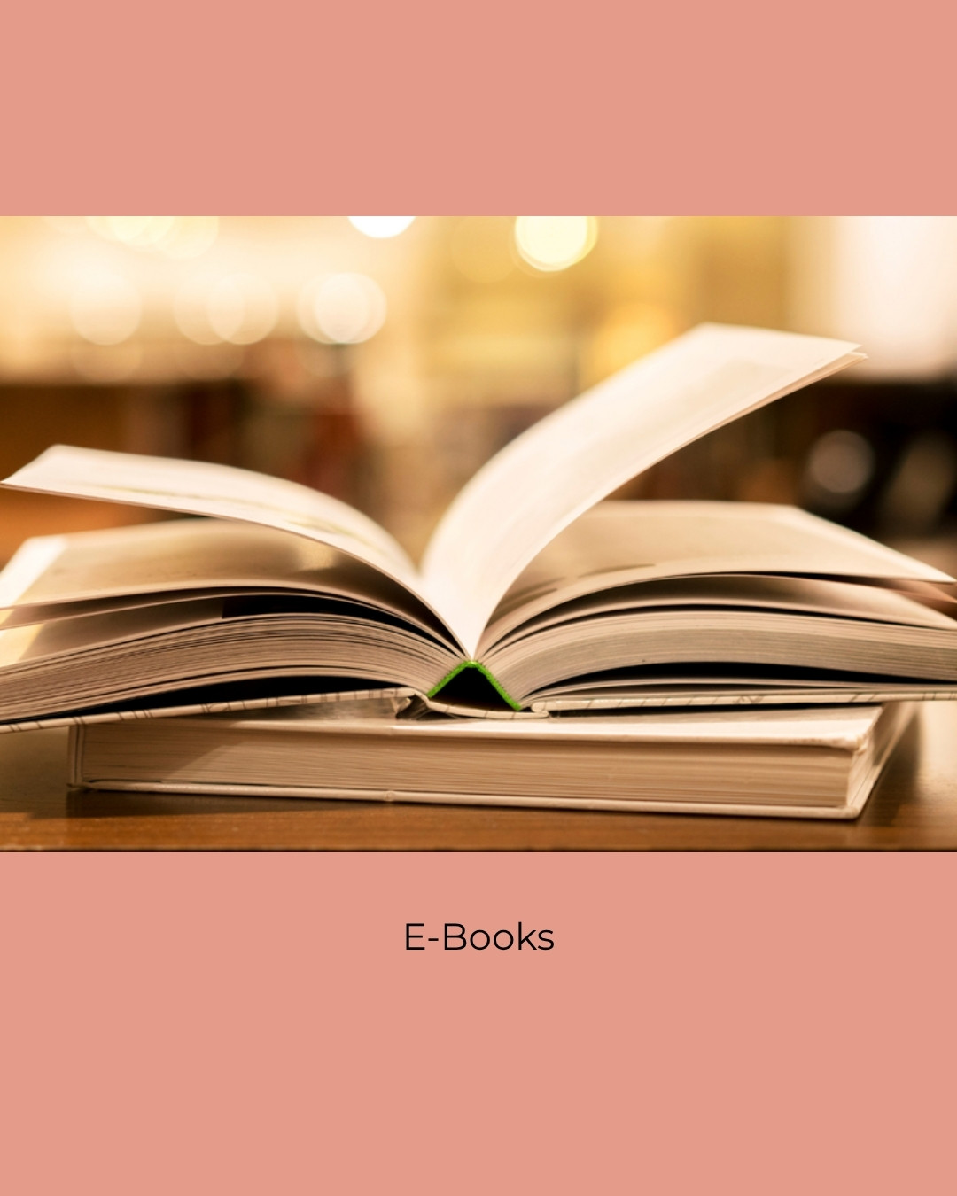 An open book resting on a table in a softly lit library. Caption: E-Books.